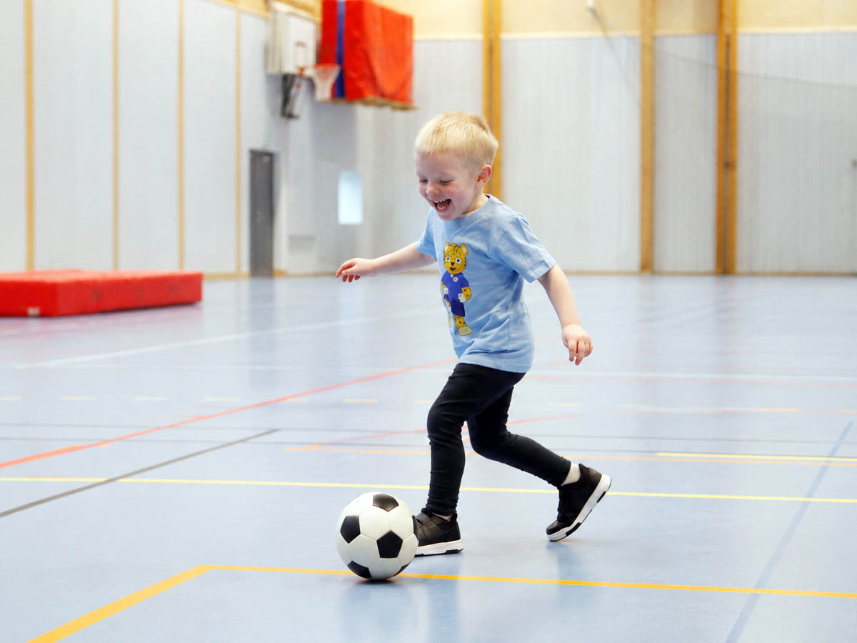 Barn springer med fotboll på Fotbollskul