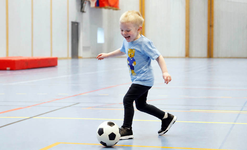 Barn springer med fotboll på Fotbollskul