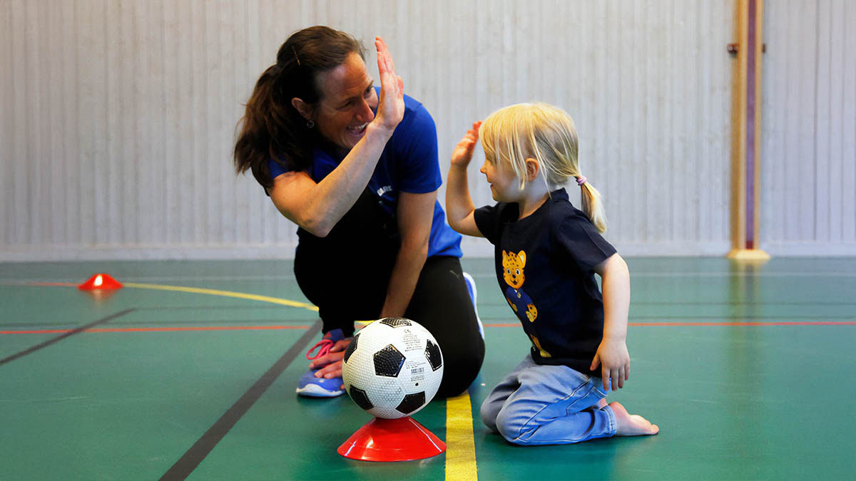 Ledare och barn ger varandra high five.